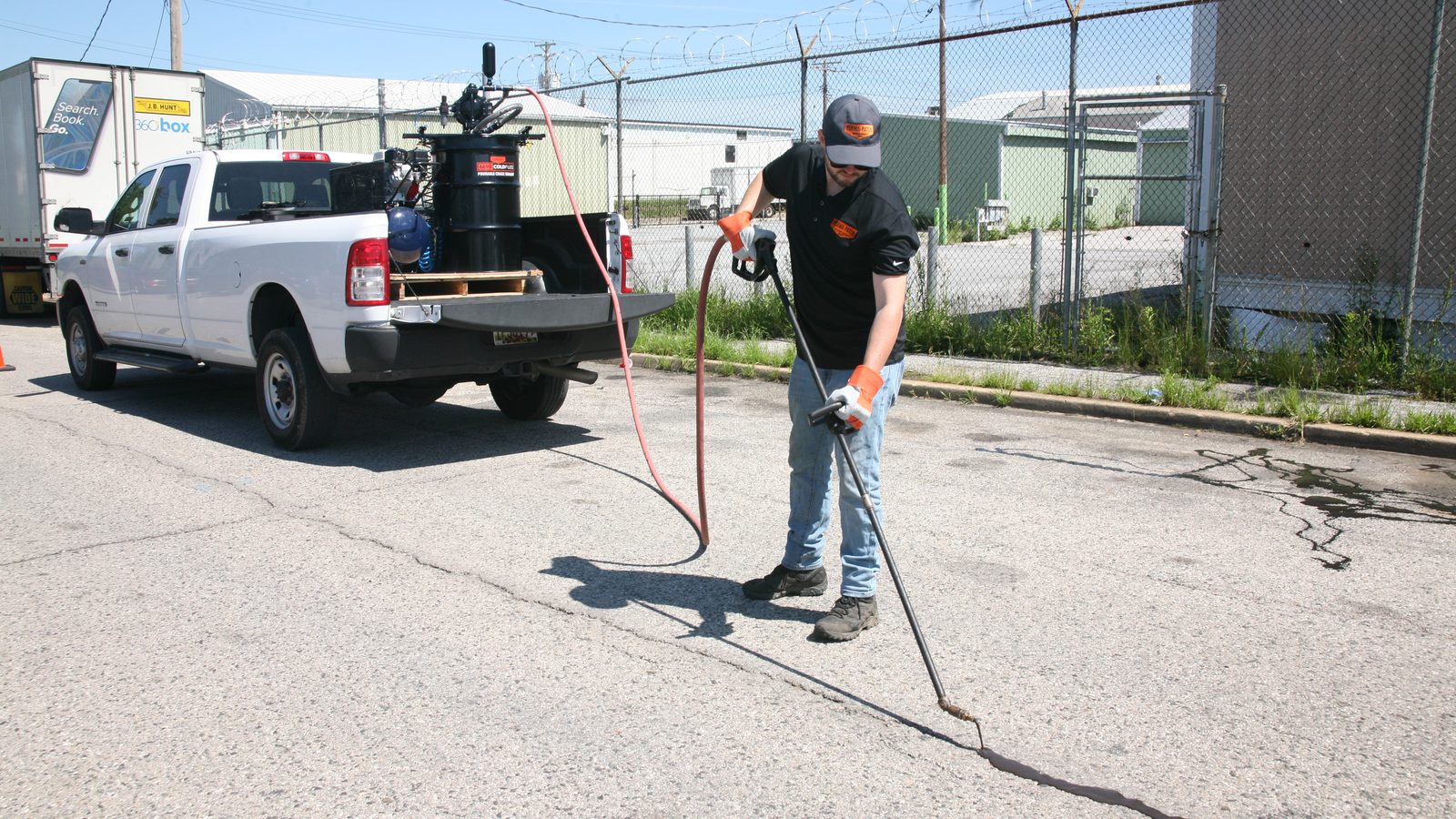 Lafayette city crew applying 6690 ColdFuze cold-applied crack sealant from a pickup truck bed with the Pump and Wand System