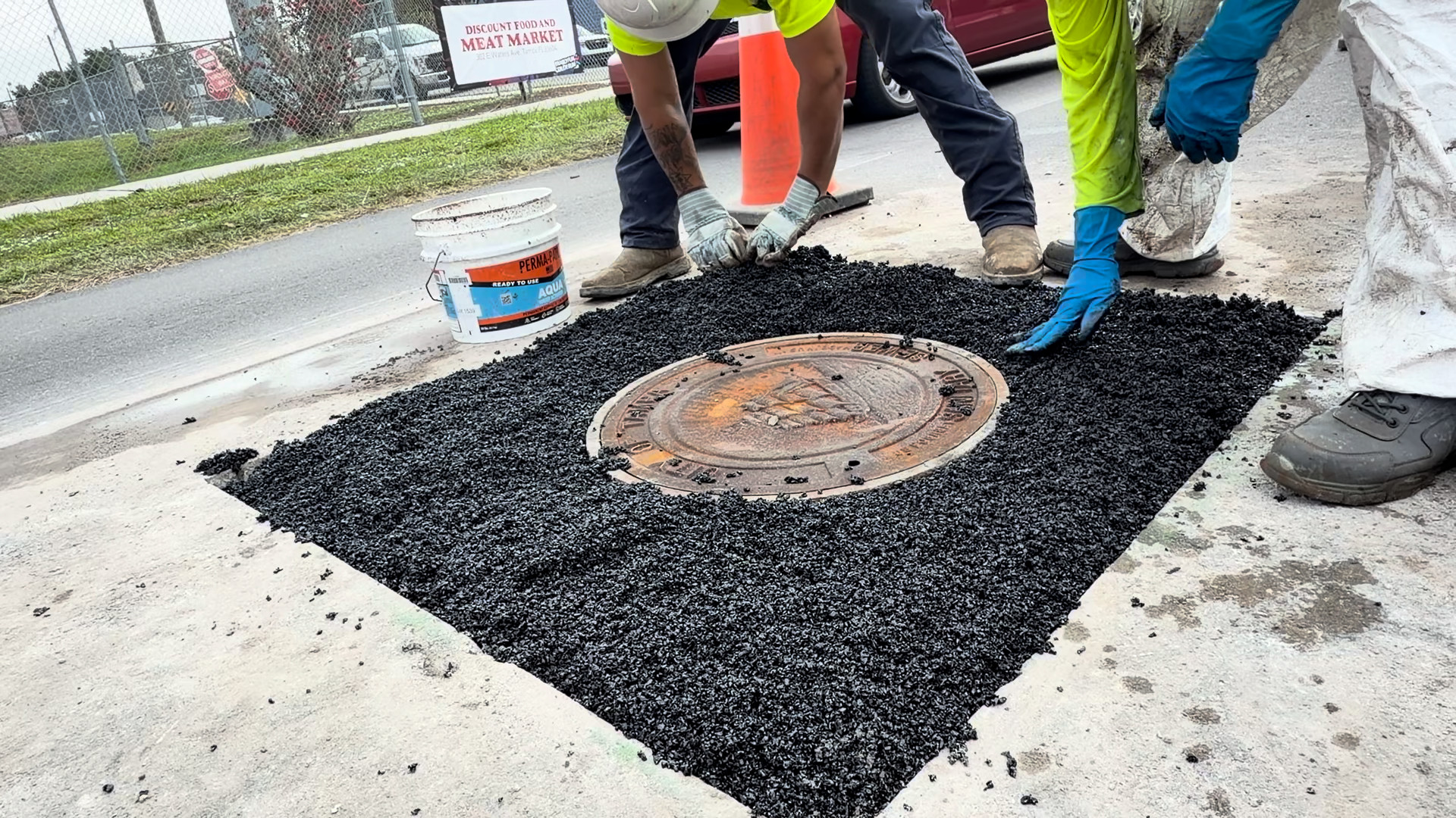 Perma-Patch Aqua placed around a City of Tampa sanitary sewer manhole frame, spread out to the saw cut