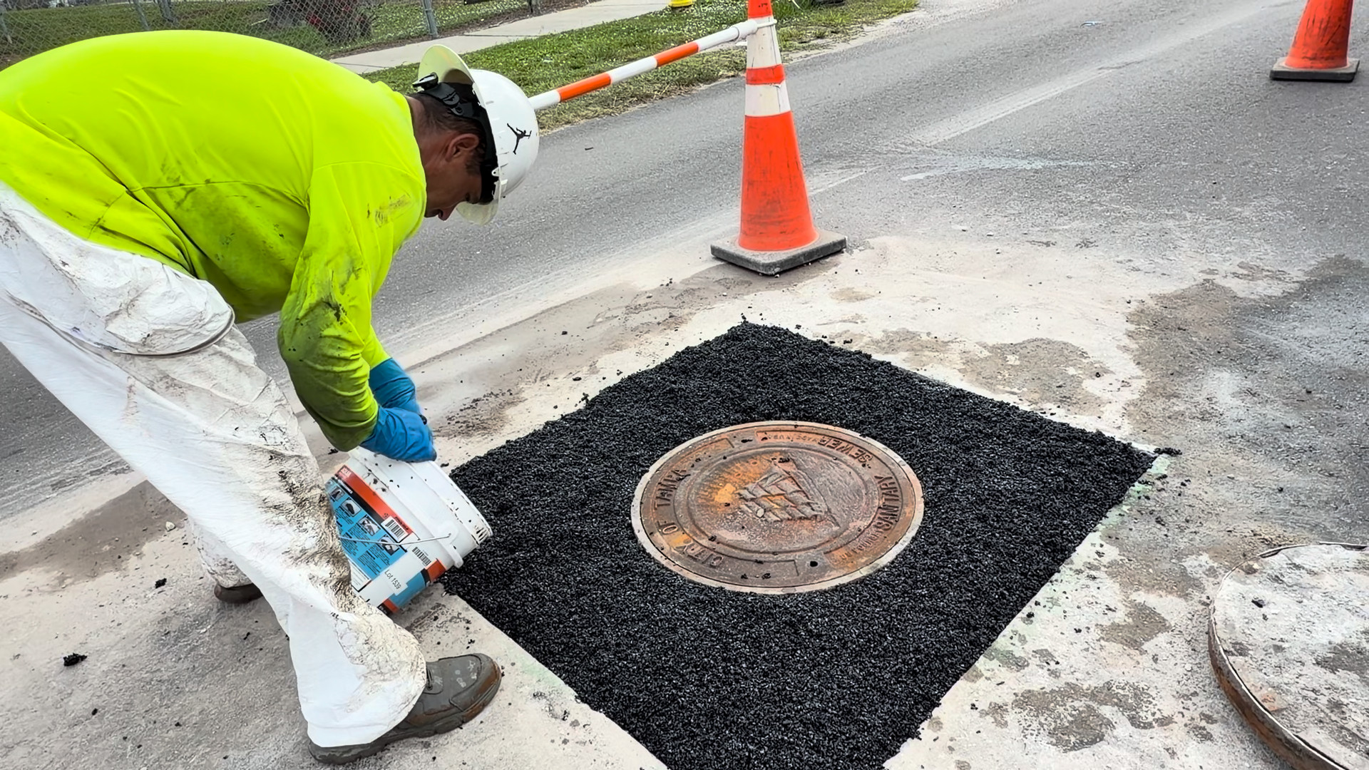 Crew member pouring Perma-Patch Aqua straight from the 50 pound pail onto the repair