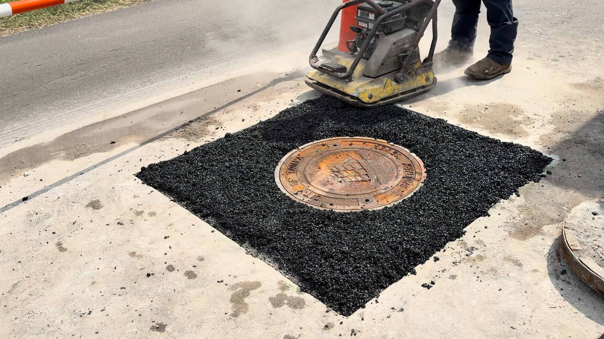 Plate compactor running across the Aqua patch around the manhole frame