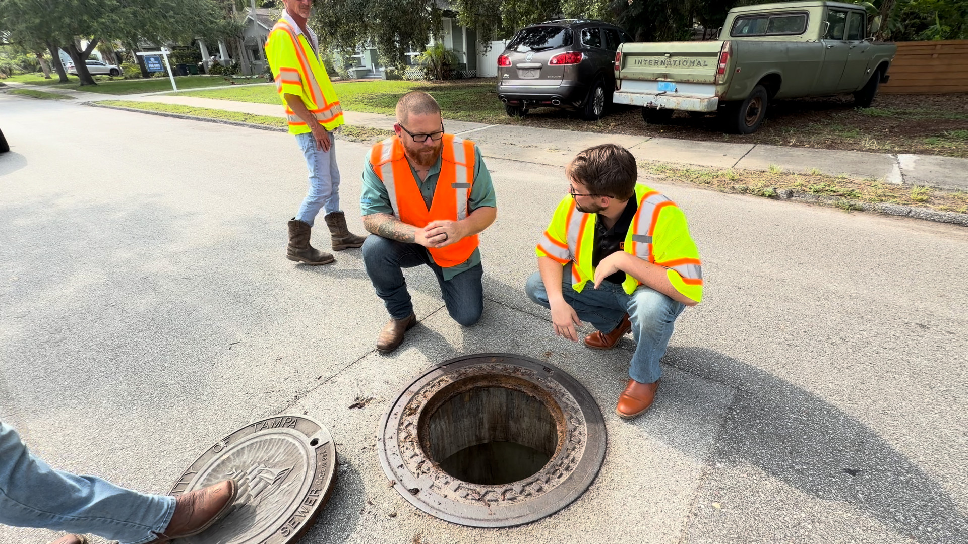 Rowland crew examining an open City of Tampa manhole with the cover set aside