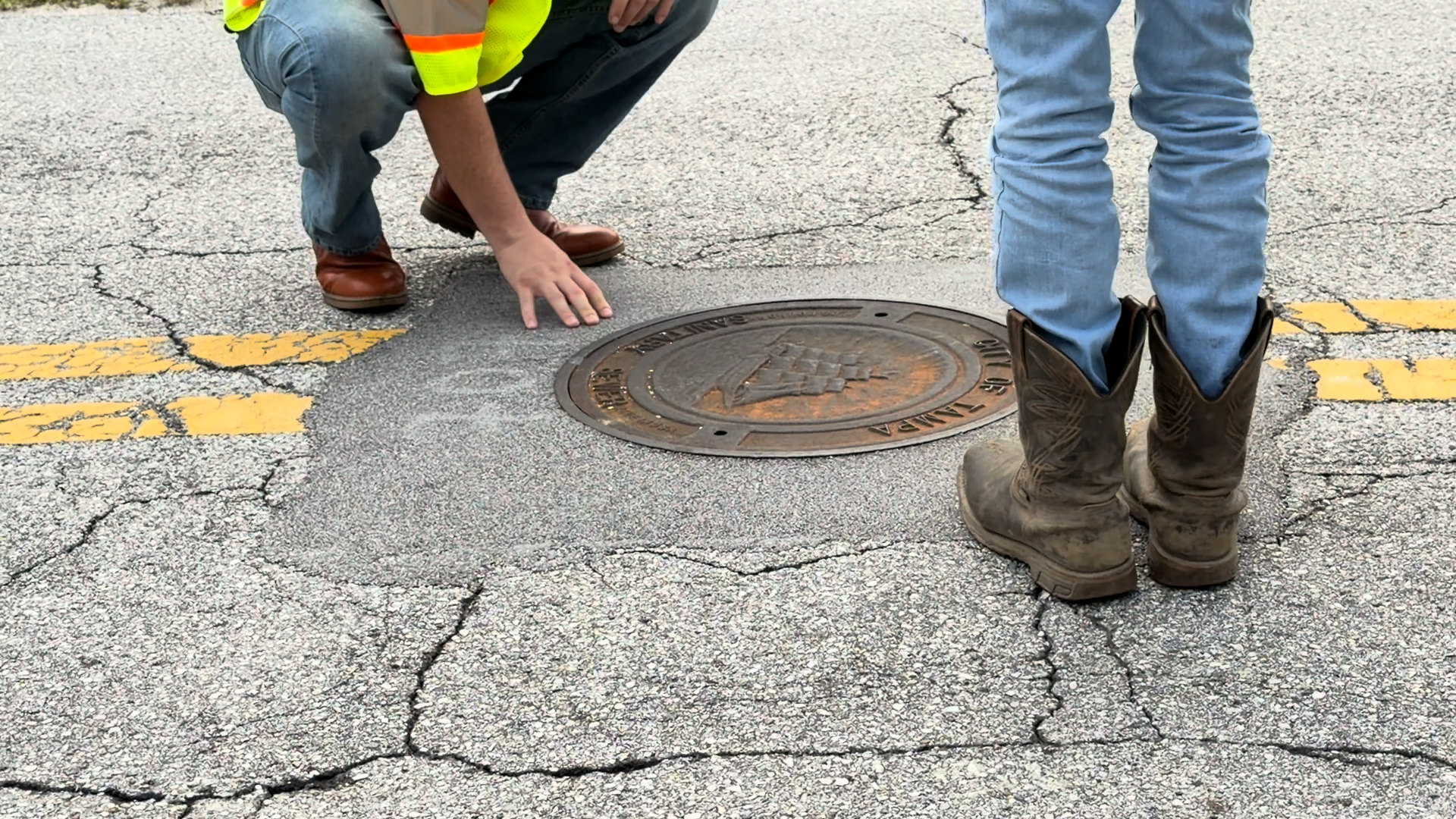 City of Tampa crew member with a hand on a Perma-Patch collar placed in 2016, the surrounding lane cracked and the collar intact