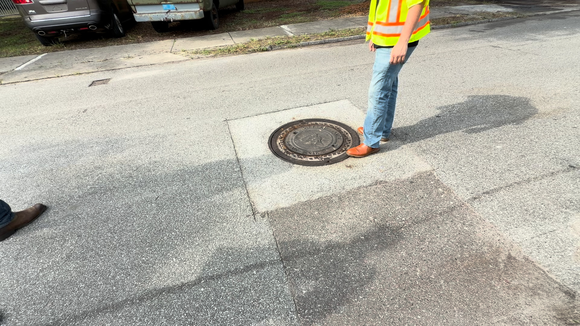 Manhole cover and its repair collar sitting flush with the travel lane on a Tampa street