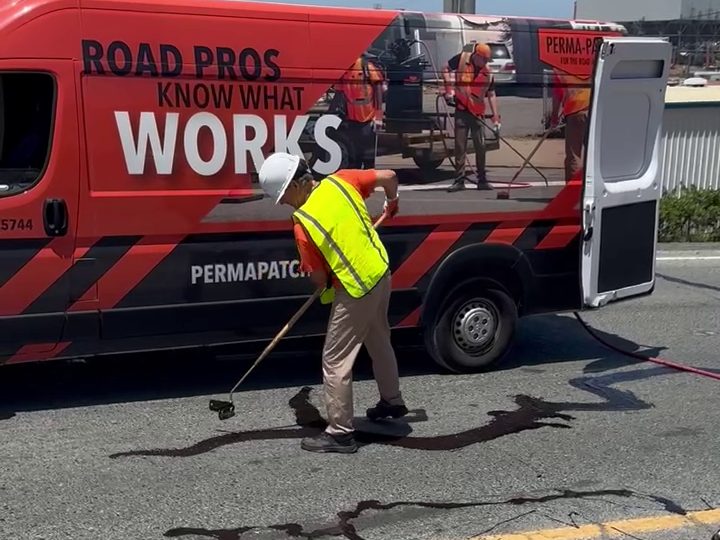Operator applying 6690 ColdFuze crack sealant with a wand alongside a Perma-Patch service van