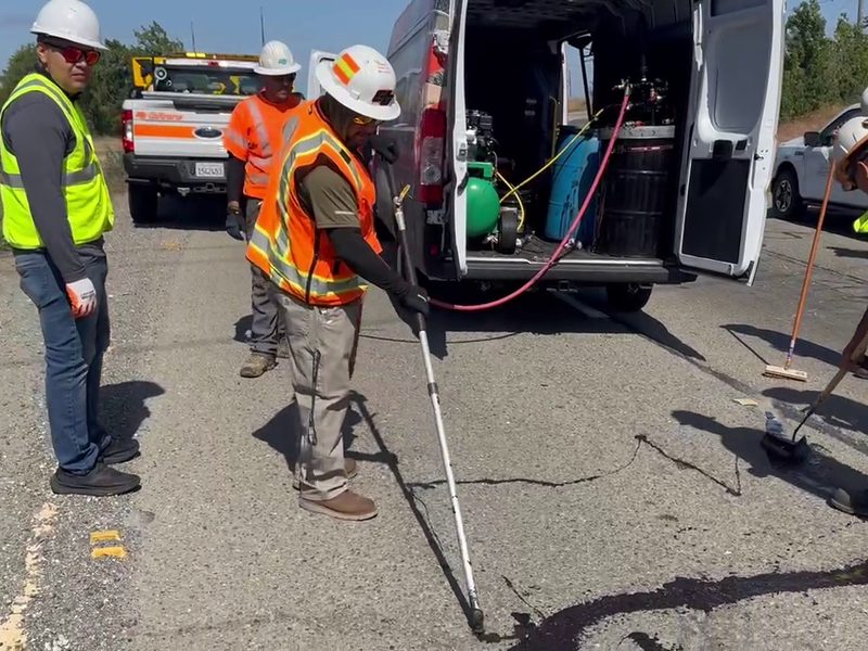Two operators working together, one applying 6690 ColdFuze with a wand while a second finishes the seal with a squeegee