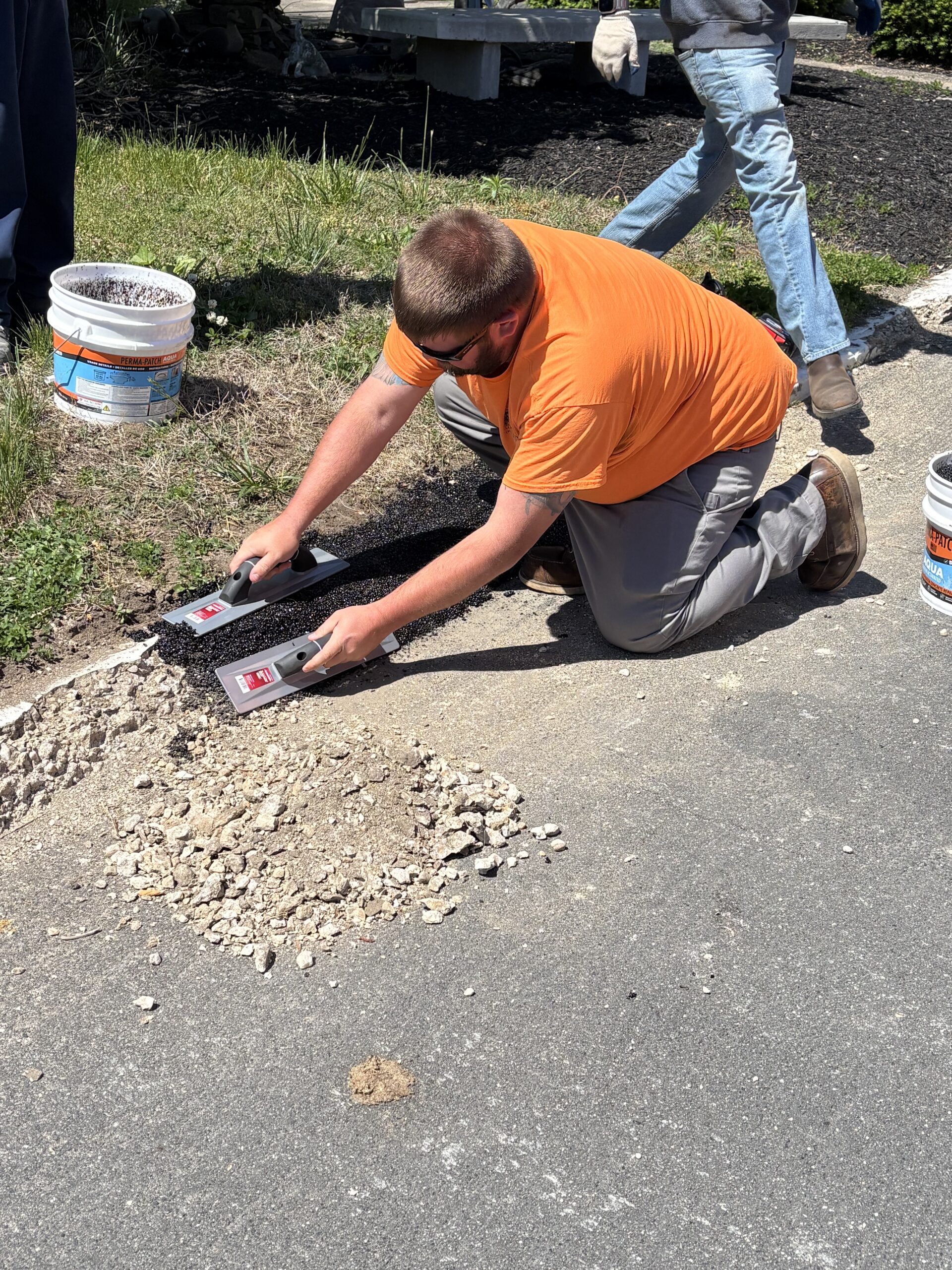 Maryland DOT field staff troweling Perma-Patch Aqua along a saw-cut Pasadena curb