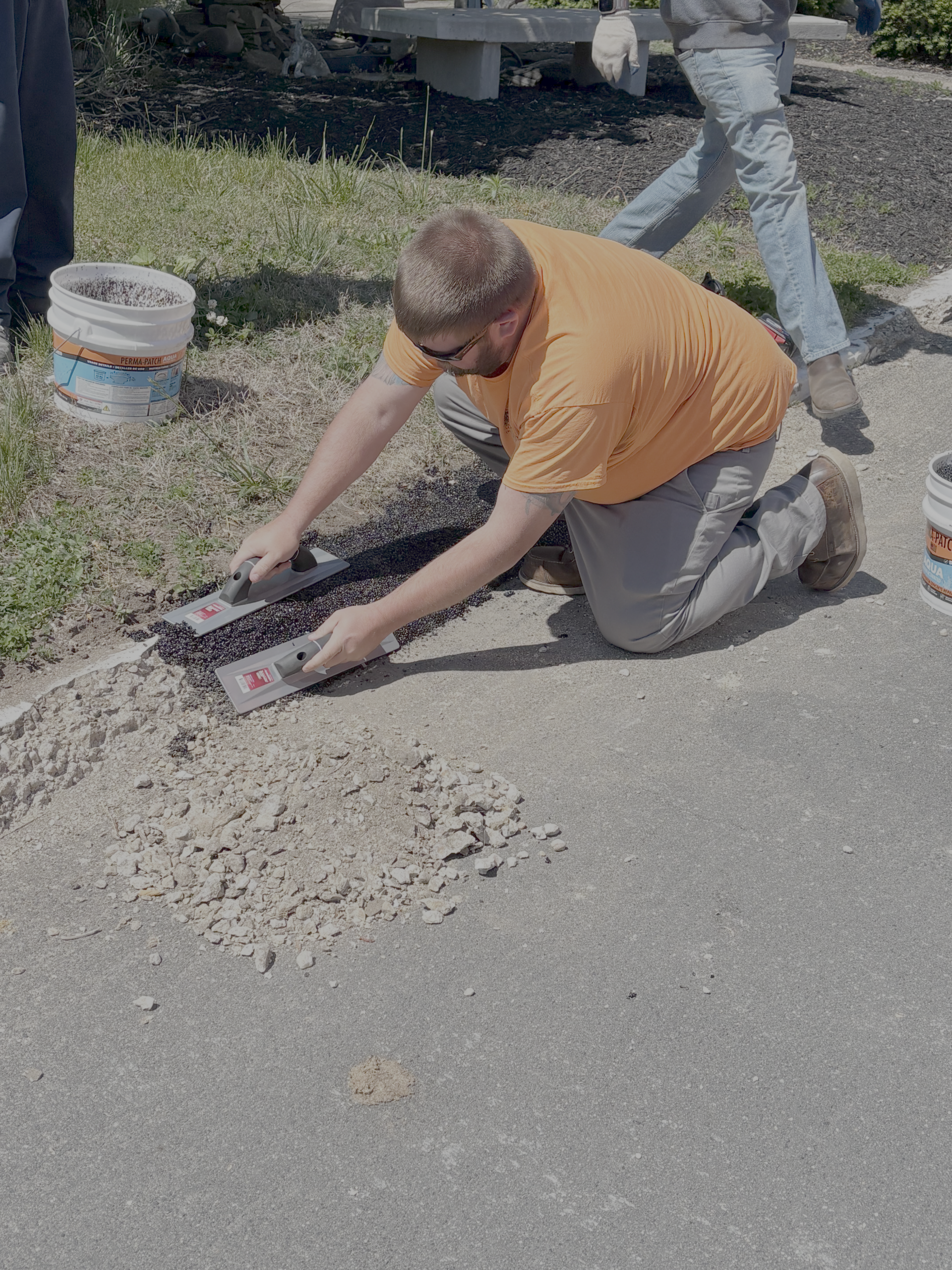 Maryland DOT field staff troweling Perma-Patch Aqua along a saw-cut Pasadena curb
