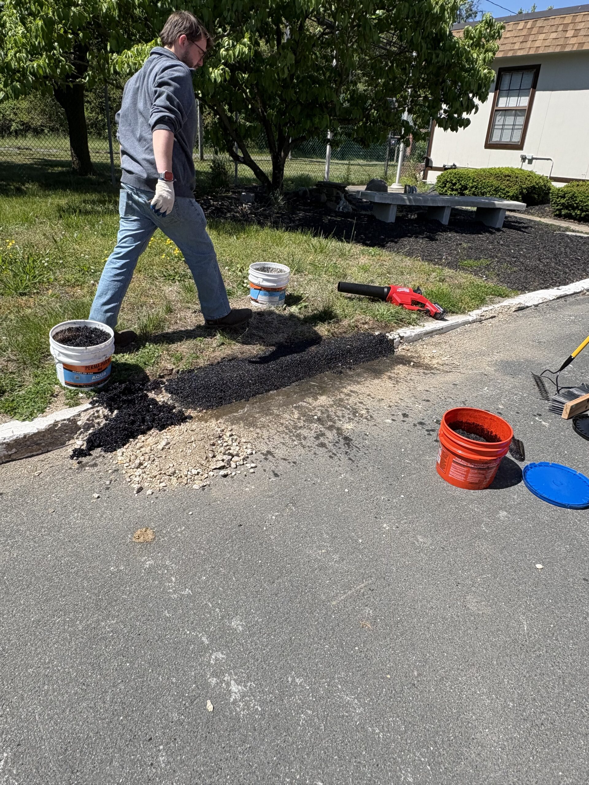 Aqua spread along the curb line from the pail, pails and hose staged on the grass