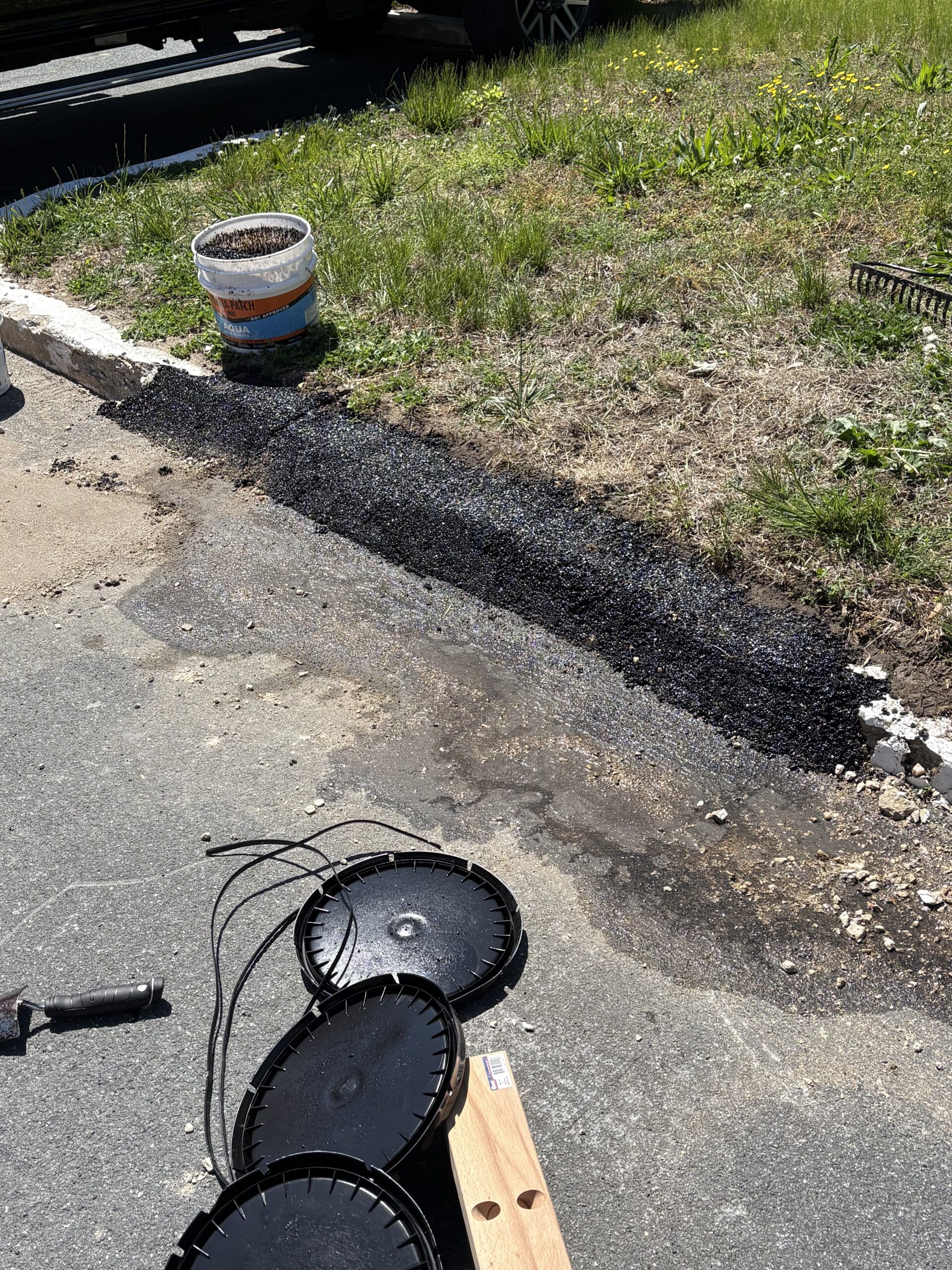 Hand compactor and pails next to a finished Aqua curb repair