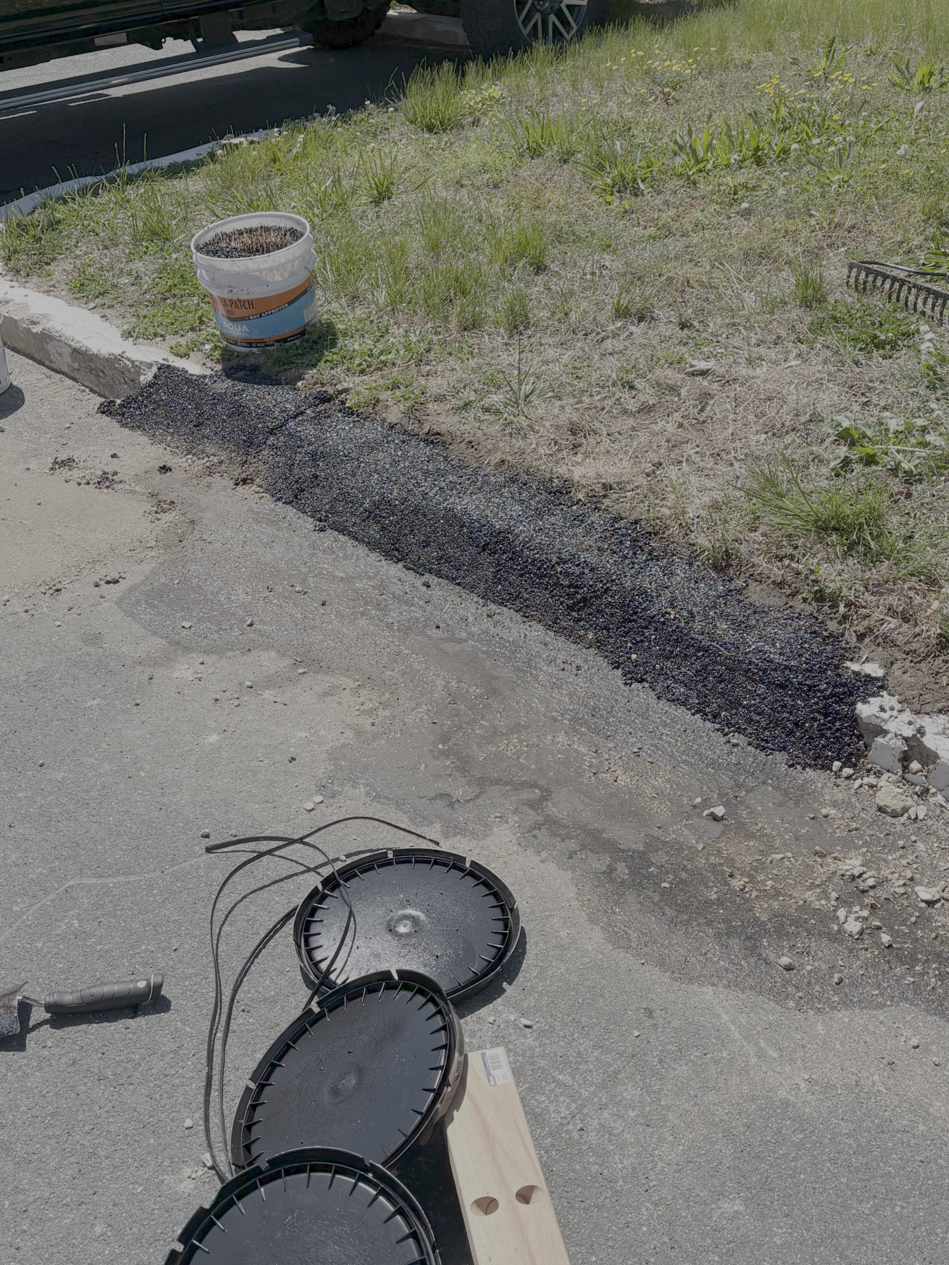 Hand compactor and pails next to a finished Aqua curb repair