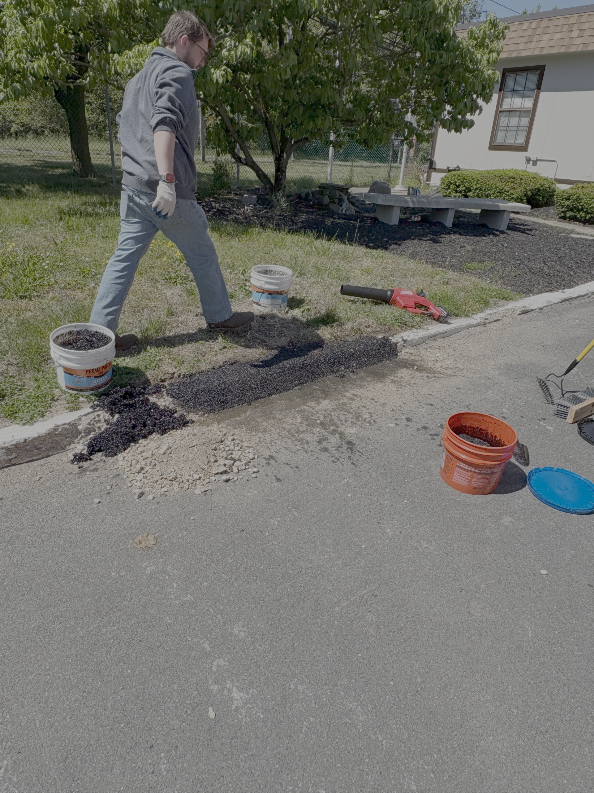 Aqua spread along the curb line from the pail, pails and hose staged on the grass